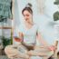 Young healthy woman using phone for setting mobile app for meditation at home,