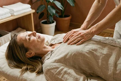 Praticienne réalisant un massage énergétique abdominal sur une femme détendue allongée sur une table de soin en studio de bien-être